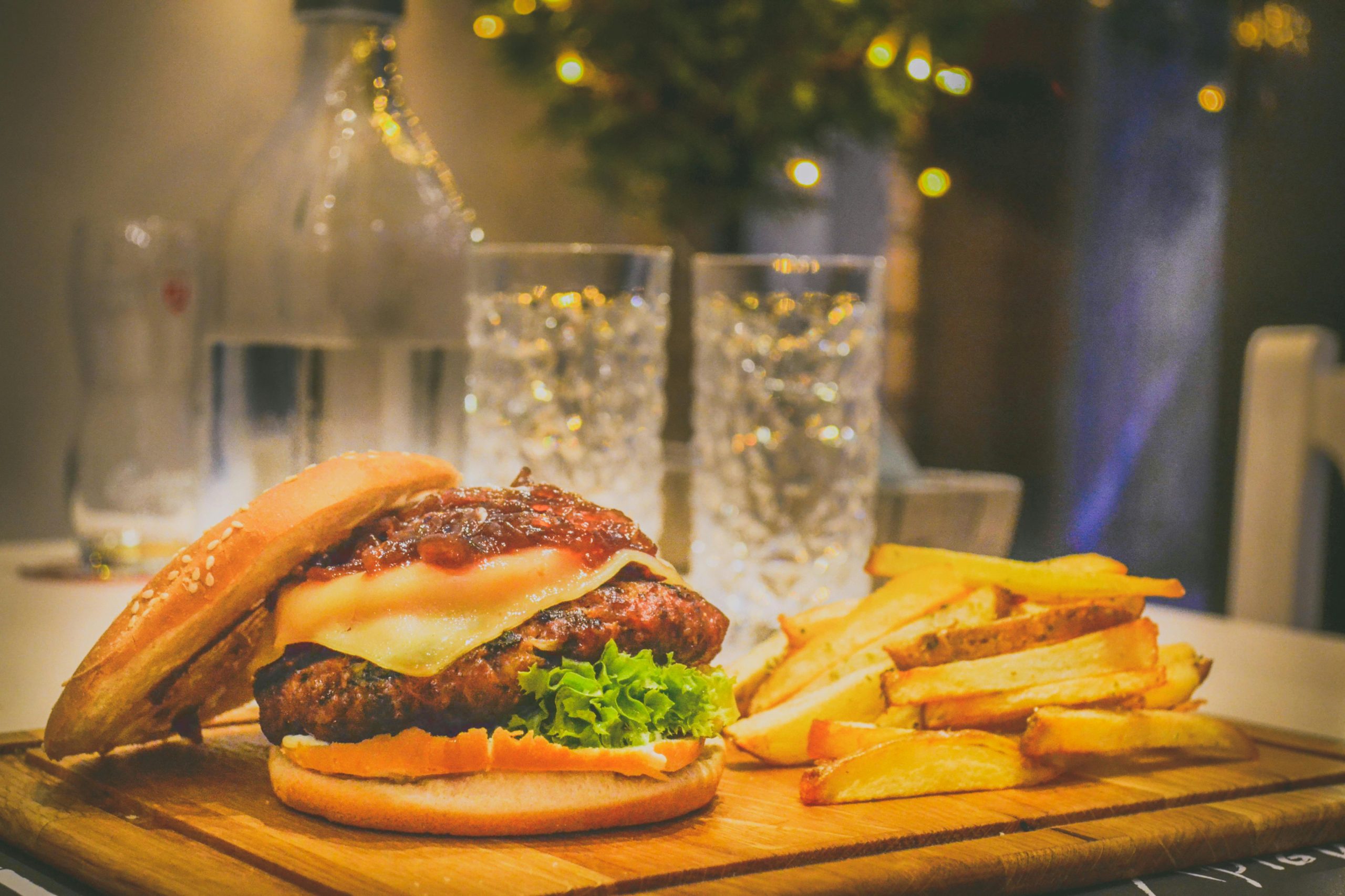 Delicious cheeseburger with lettuce and fries on a wooden board, perfect for a fast food meal.